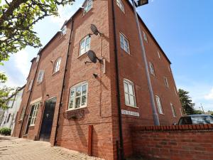 un edificio de ladrillo rojo con ventanas en una calle en The Old Bakery, Apartment 5, en Shipston on Stour