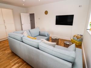 ein Wohnzimmer mit einem blauen Sofa und einem Flachbild-TV in der Unterkunft The Old Bakery, Apartment 5 in Shipston on Stour