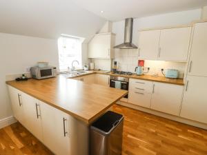 a kitchen with white cabinets and a wooden counter top at The Old Bakery, Apartment 5 in Shipston-on-Stour