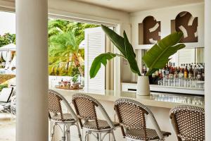 a restaurant with chairs and a bar with a plant at Malliouhana Resort Anguilla in Meads Bay