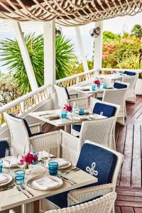 a restaurant with tables and chairs on a deck at Malliouhana Resort Anguilla in Meads Bay