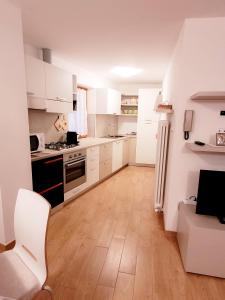 uma cozinha com armários brancos e piso em madeira em Appartamento Rosina, per 4/6 persone. In centro em Coredo