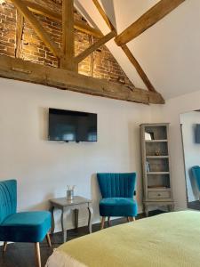 a bedroom with two blue chairs and a tv at Upstairs at 33 - Self check in boutique accommodation in Worcester Centre in Worcester