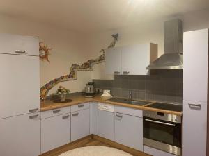 a kitchen with white cabinets and a sink at Schilcherland-Apartment in Stainz