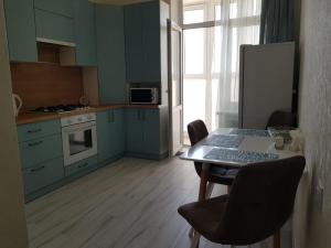 a kitchen with blue cabinets and a table with chairs at MY GUEST - 1К квартира в ЖК Российский in Stavropol