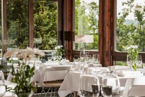 un comedor con mesas y sillas blancas y ventanas en Hotel Njord, en Hahnenklee-Bockswiese