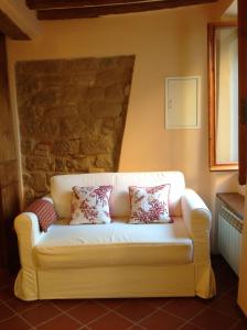 a white couch in a room with a stone wall at Pinturicchio, Characteristic and comfortable apartment in the historic center in Perugia