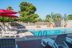 a swimming pool with chairs and a red umbrella at Luxury Beachfront Apartment Taormina Pool and Parking in Taormina