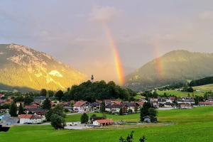 een regenboog over een klein stadje met huizen en bergen bij Ferienwohnung Otto in Ruhpolding
