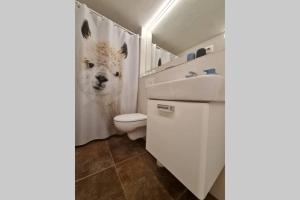 een badkamer met een wit toilet en een witte hond op het douchegordijn bij Ferienwohnung Otto in Ruhpolding