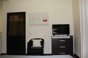 1 dormitorio con TV, silla y puerta en Room Seaview, en Câmara de Lobos