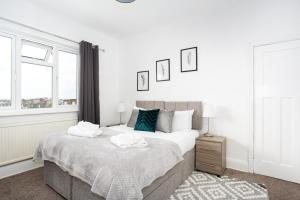 ein weißes Schlafzimmer mit einem großen Bett und zwei Fenstern in der Unterkunft The Woodgrange by Sorted Stay in Southend-on-Sea