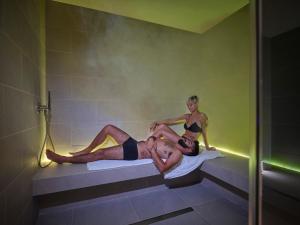 Un uomo e una donna seduti in una vasca da bagno di Hotel L'Esagono a San Teodoro