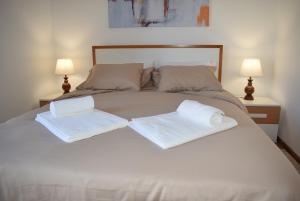 uma cama branca com duas toalhas brancas em Terreiro da Erva House em Coimbra