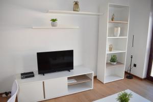 uma sala de estar com uma televisão num armário branco em Terreiro da Erva House em Coimbra