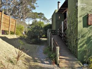 einen Holzweg, der zu einem Haus mit einem Zaun führt in der Unterkunft Ave Fénix, un lugar mágico para disfrutar. in Punta Del Diablo