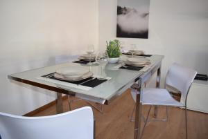mesa de comedor con sillas blancas y mesa con gafas en Terreiro da Erva House, en Coímbra