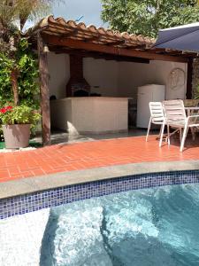 a swimming pool with a table and chairs next to a house at Guesthouse Mata da Praia in Vitória