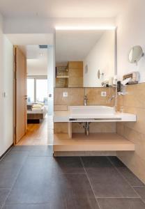 a bathroom with a sink and a large mirror at Boutiquehotel zur Winzerstube - Adults Only in Hagnau