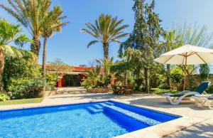 a swimming pool with an umbrella and palm trees at Villa Rosa in Sant Josep de sa Talaia