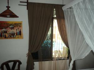 a bedroom with a window with curtains and a chair at Villa Kumi in Nungwi