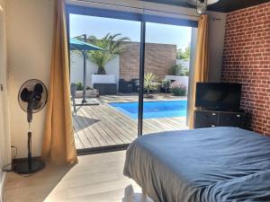 a bedroom with a view of a pool and a fan at Villa Bellenbois avec piscine privée , proche La Rochelle in Sainte-Soulle
