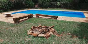 a fire pit and a bench next to a pool at Pousada Casa do Fabio - Bikers point in Águas da Prata +7 photos