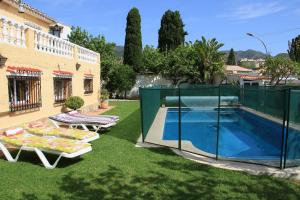 un patio trasero con piscina y 2 tumbonas en Casa de los Limones by Costadelsolholiday FAMILY VILLA NEAR PUERTO MARINA, en Benalmádena