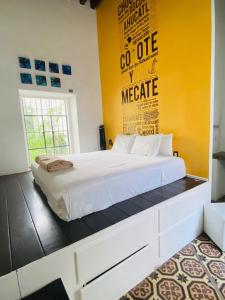 1 dormitorio con cama blanca y pared amarilla en Kuku Ruku Hotel, en Querétaro