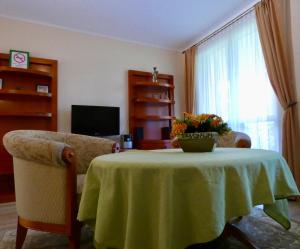 a living room with a table and a couch and a window at Fortuna Golf Apartman in Bük