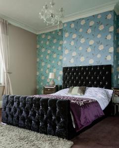 a bedroom with a large bed with a blue wall at Southfield lodge in Middlesbrough