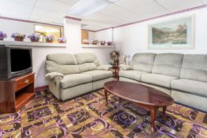 a living room with couches and a table and a tv at Days Inn by Wyndham Sanford in Sanford