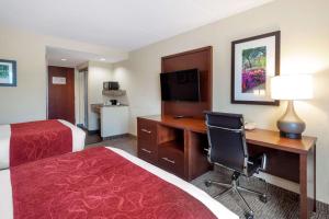 a hotel room with a desk and a bed at Comfort Suites Fredericksburg North in Fredericksburg