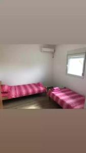 two pink beds in a room with a window at Smestaj sobe di camera uno in Subotica
