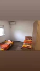 two twin beds in a room with a window at Smestaj sobe di camera uno in Subotica