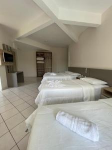 um quarto com quatro camas brancas num quarto em Termas Park Hotel em Gravatal