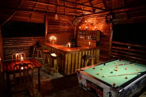 un pub con mesa de billar y un bar con velas en Kibale Guest Cottages, en Fort Portal