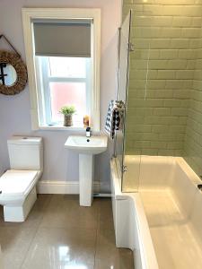 uma casa de banho com um lavatório, uma banheira e um WC. em Seaside Sundae Suite em Lytham St Annes