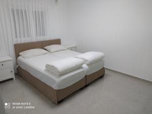 a bedroom with a bed with white sheets and pillows at בית במושב in Ẕafriyya