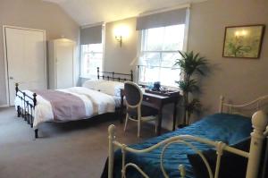 a bedroom with two beds and a desk and a table at The Crown Inn, Kemerton in Tewkesbury