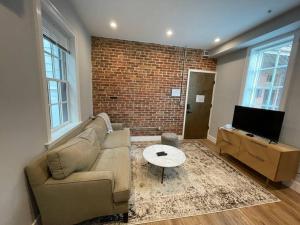 uma sala de estar com um sofá e uma parede de tijolos em The King Suite at Prince Street Inn ADA Accessible em Alexandria