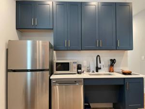 a kitchen with blue cabinets and a stainless steel refrigerator at The King Suite at Prince Street Inn ADA Accessible in Alexandria