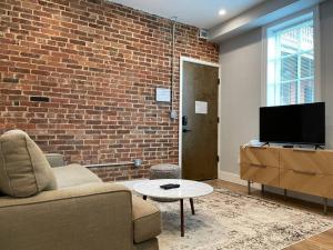 a living room with a couch and a brick wall at The King Suite at Prince Street Inn ADA Accessible in Alexandria