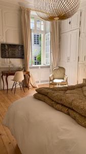 a bedroom with a bed and a chair and a window at L'APPARTEMENT by Merveilles de Marie in Lons-le-Saunier