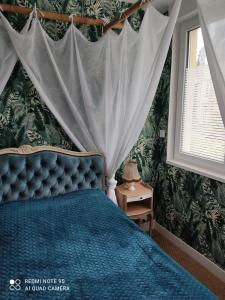 - une chambre avec un lit bleu à baldaquin dans l'établissement Au repos des baigneurs, appartement rez-de-chaussée, WIFI, au Tréport