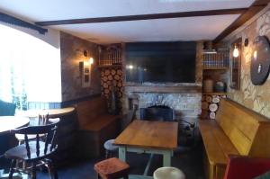 un bar con chimenea, mesa y TV en The Crown Inn, Kemerton en Tewkesbury