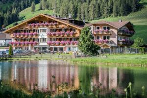 a large building with flowers on it next to a lake at Hotel Waldheim in Sesto