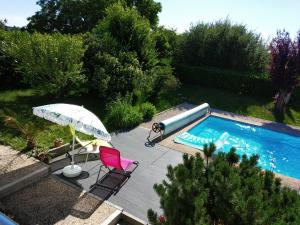 a swimming pool with a pink chair and an umbrella at Une HALTE Quelque PART in Cheminot