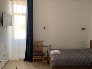 1 dormitorio con 1 cama, 1 silla y 1 ventana en ZIG ZAG, en Kamianets-Podilskyi