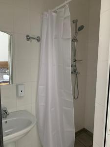 baño con cortina de ducha blanca y lavamanos en ZIG ZAG, en Kamianets-Podilskyi